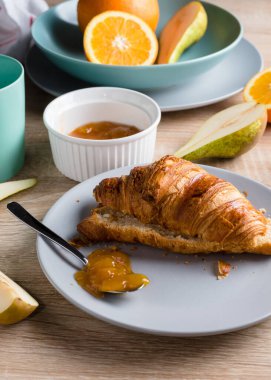 Sağlıklı kahvaltı. Kruvasan, çörek, kahve, reçel, meyve: portakal ve armut.. 
