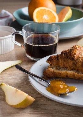 Sağlıklı kahvaltı. Kruvasan, çörek, kahve, reçel, meyve: portakal ve armut.. 