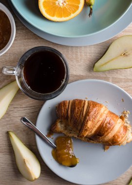 Sağlıklı kahvaltı. Kruvasan, çörek, kahve, reçel, meyve: portakal ve armut.. 