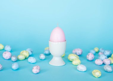 Paskalya kartı. Paskalya porselen tavşanı, boyalı yumurtalar ve mavi arka planda beyaz bir saksıda sarı bir çiçek. Sarı-mavi konsept.