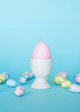 Paskalya kartı. Paskalya porselen tavşanı, boyalı yumurtalar ve mavi arka planda beyaz bir saksıda sarı bir çiçek. Sarı-mavi konsept.