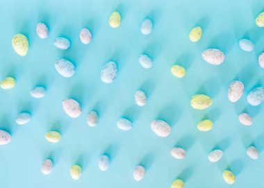 Paskalya kartı. Paskalya porselen tavşanı, boyalı yumurtalar ve mavi arka planda beyaz bir saksıda sarı bir çiçek. Sarı-mavi konsept.