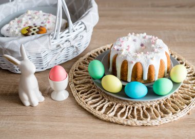 Güzel Paskalya kartı. Paskalya pastası, yumurta, porselen tavşan ve masada beyaz bir sepet. Minimum konsept. Kırsal biçim