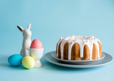 Lezzetli Paskalya pastaları ve yumurtalar, mavi arka planda Paskalya tavşanı. Minimum konsept. Boşluğu kopyala.