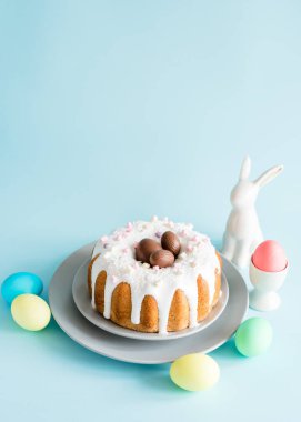 Lezzetli Paskalya pastaları ve yumurtalar, mavi arka planda Paskalya tavşanı. Minimum konsept. Boşluğu kopyala.