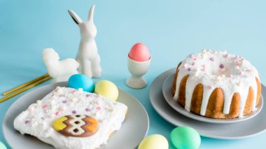 Lezzetli Paskalya pastaları ve yumurtalar, mavi arka planda Paskalya tavşanı. Asgari konsept. 