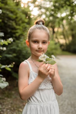 Gün batımında elinde küçük bir buket yasemin olan küçük bir kız. Anneler Günü, bahar