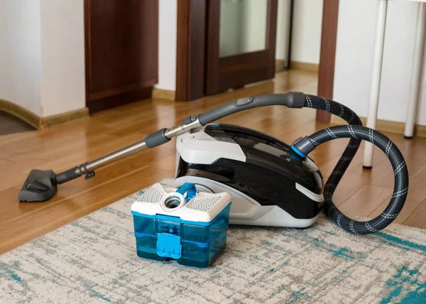 The washing vacuum cleaner stands in the center of the room after cleaning. Vacuum cleaner tank with dirty water after cleaning. Cleaning concept.