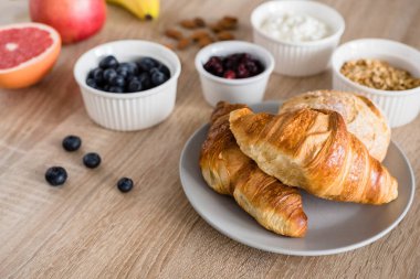 Sağlıklı kahvaltı. Yabanmersini, süzme peynir, greyfurt, yulaf ezmesi, kuru kızılcık, badem, taze kruvasan ve çörek. Uzun biçim pankartı