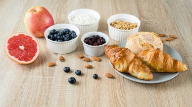 Sağlıklı kahvaltı. Yabanmersini, süzme peynir, greyfurt, yulaf ezmesi, kuru kızılcık, badem, taze kruvasan ve çörek. Uzun biçim pankartı