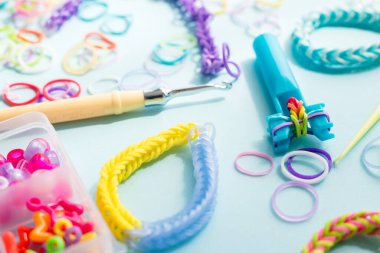 Mavi arka planda elastik bantlarla dekoratif bilezik yapmaya yakın çekim. Loom bilezikleri