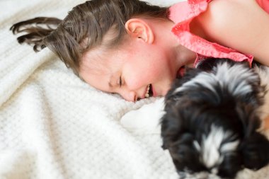 7 yaşında bir kız bir Shih Tzu köpeğiyle oynuyor.
