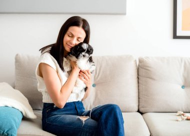 Genç ve güzel bir kadın bir shih tzu köpeğine sarılıyor ve nazikçe okşuyor. Hayvanlar ve insan dostluğu