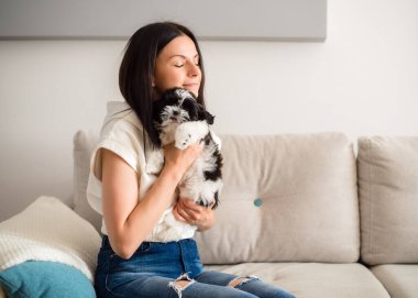 Genç ve güzel bir kadın bir shih tzu köpeğine sarılıyor ve nazikçe okşuyor. Hayvanlar ve insan dostluğu