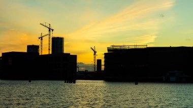 Gün batımında kule inşaat vinçleri ve binalar. Kopenhag 'da inşaat ve gayrimenkul. Danimarka. İnşaat arkaplanı.