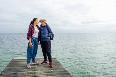 İki güzel kadın denize tahta bir iskeleden bakıyor. Özgürlük için. Seyahat.