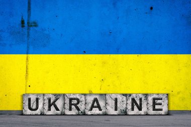 Ukrayna, taş bloklardaki kelimeler, Ukrayna bayrağının grunge arkaplanı, beton bir duvar. Uzayı kopyala İşaretler ve semboller. Ülkeler..
