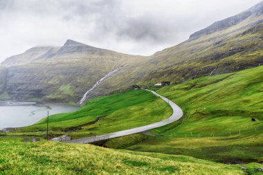 Güzel dağların ve deniz koyunun yanındaki yol. Faroe Adaları. Danimarka, Avrupa. Manzaralar. Doğa. Seyahat konsepti arka planı