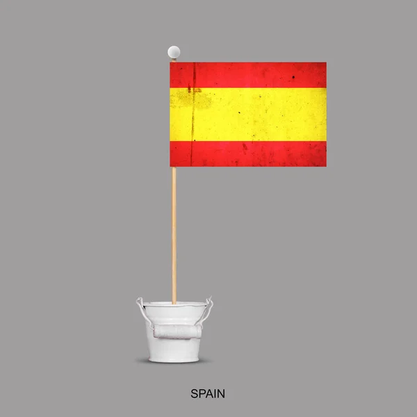 Grunge flag of Spain on a stick, in a small bucket. Isolated on a gray background. Signs and symbols. Flags.Design element.