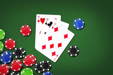Üç yedili ve yeşil arka planda poker fişleri. kopyalama alanı. Kumar. Arkaplan.