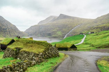 Güzel dağların ve deniz koyunun yanındaki yol. Faroe Adaları. Danimarka, Avrupa. Manzaralar. Doğa. Seyahat konsepti arka planı