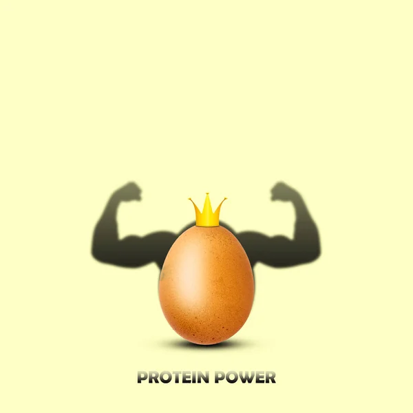 Chicken egg in a crown casts a shadow with biceps. Protein source. Sport. Healthy food. Diet. Proper nutrition. Lifestyle.