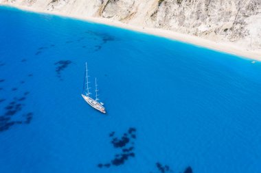 Lefkada, Yunanistan. Uzak beyaz Egremni plajı, İyon Denizi 'ndeki turkuaz renkli körfezde lüks bir yat teknesi var.