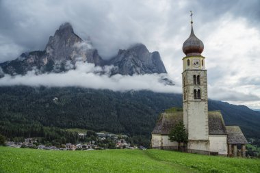 St Valentines Kilisesi, Seis am Schlern, İtalya. Arkaplanda yağmur bulutları olan Schlern Dağı