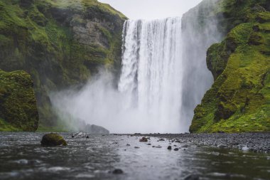 Güzel Skogafoss şelalesi. İzlanda 'nın en popüler yeri. Su, nehrin aşağısındaki güzel bir vadiden aşağı dökülüyor.