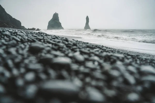 Stenen op een zwart strand op humeurige dag in IJsland — Stockfoto