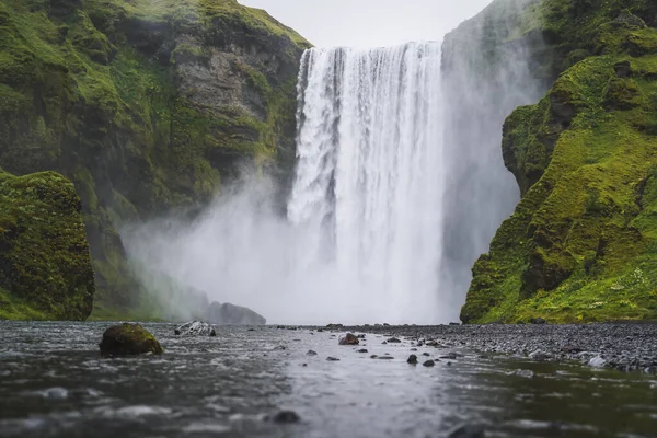 Gyönyörű Skogafoss vízesés. Izland legnépszerűbb úti célja. Víz esik le egy gyönyörű völgy épület tükörképe a folyó alatt — Stock Fotó
