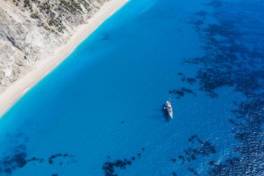 Lefkada, Yunanistan. Uzak beyaz Egremni plajı, İyon Denizi 'ndeki turkuaz renkli körfezde lüks bir yat teknesi var..