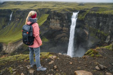 Sırt çantalı kadın İzlanda İskoç şelalesinin keyfini çıkarıyor..