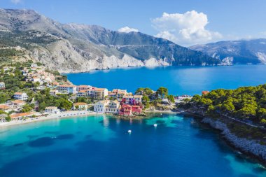 Assos, Yunanistan 'ın Kefalonia kentinin yukarısından güzel bir balıkçı köyü. Erial drone görüntüsü. Yelkenli tekneler turkuaz körfezde demirlemiş..