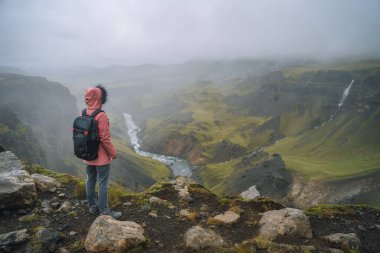 Sırt çantalı kadın Haifoss şelalesinin yakınındaki fossa nehrinin üzerinde. İzlanda İskoçya.