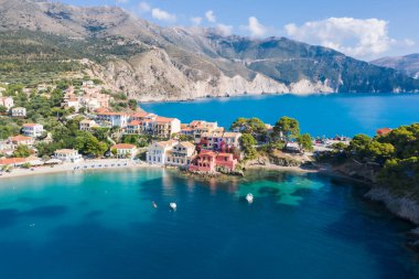 Yunanistan 'ın Kefalonya kentindeki Assos adlı balıkçı köyüne panoramik hava manzarası. Turkuaz denizin üzerinde demirlemiş yelkenli gemiler..
