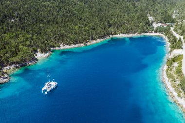 Foki Sahili 'nin panoramik hava manzarası ve turkuaz körfeze demirlemiş yelkenli tekneleri. Fiskardo, Kefalonia Adası, Yunanistan.