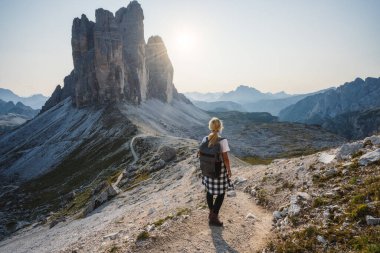 Sırt çantalı kadın yürüyüşçü gün batımında Tre Cime di Lavaredo 'nun tadını çıkarıyor. Dolomitler, İtalya.
