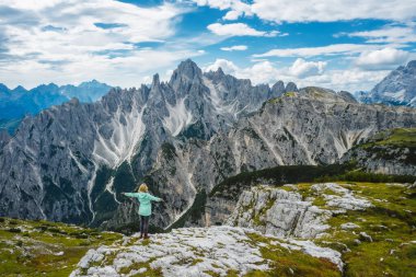 İtalyan Alpleri, Dolomitler, İtalya ve Avrupa 'nın Cadini di Misurina dağlarına hayran olan yeşil ceketli bir kadın yürüyüşçünün hava görüntüsü..