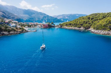 Assos, Yunanistan 'ın Kefalonia kentinin yukarısından güzel bir balıkçı köyü. Hava aracı görüntüsü. Yelkenli tekneler turkuaz körfezde demirlemiş..