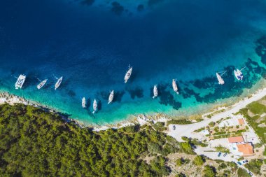 Fiskardo, Kefalonia adası, İyonya, Yunanistan 'ın mavi körfezine yanaşmış yelkenli teknelerinin yukarıdan aşağıya bakan görüntüsü.