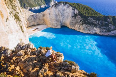 Yunanistan 'ın Zakynthos Adası' ndaki gemi enkazı plajından keyif alan kadın turistin hava manzarası. Yaz yolculuğu konsepti.