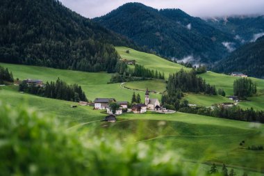 Val di Funes Vadisi 'ndeki St. Magdalena Kilisesi, Dolomitler, İtalya. Arkaplanda Furchetta ve Sass Rigais dağ zirveleri.