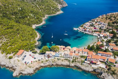 Assos, Yunanistan 'ın Kefalonia kentinin yukarısından güzel bir balıkçı köyü. Erial drone görüntüsü. Yelkenli tekneler turkuaz körfezde demirlemiş..