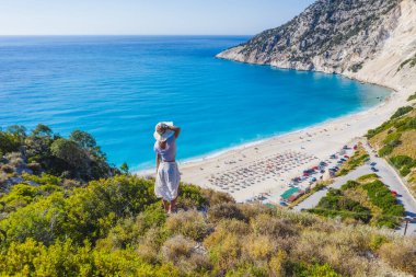 Myrtos Sahili 'nin tadını çıkaran şapkalı mutlu bir kadın. Sefalonya Adası, Yunanistan.