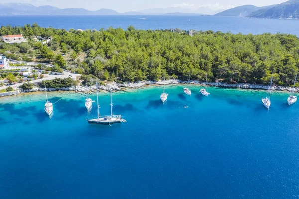 Aerial photo of sailing boats docked in blue bay of Fiskardo, Kefalonia island, Ionian, Greece.