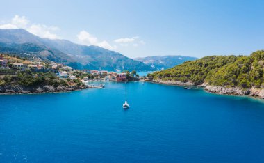 Assos, Yunanistan 'ın Kefalonia kentinin yukarısından güzel bir balıkçı köyü. Hava aracı görüntüsü. Yelkenli tekneler turkuaz körfezde demirlemiş..