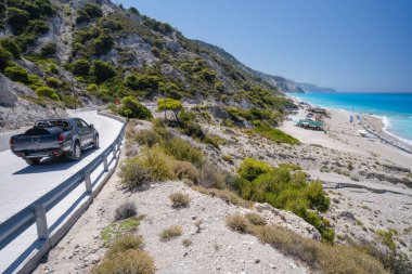 Yunanistan 'ın Lefkada İyon adasındaki sahil yolunda turist arabası.
