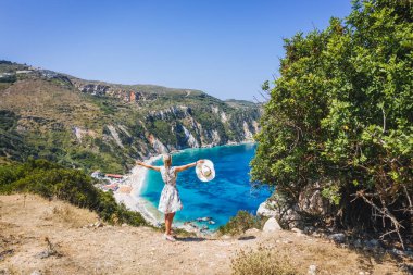 Mutlu kadın, heyecan verici bir özgürlük duygusuyla el kaldırıyor ve Petani Sahili 'ne bakıyor. Sefalonya Adası, Yunanistan.