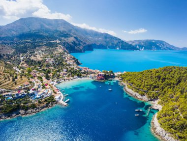 Yunanistan 'ın Kefalonya kentindeki Assos adlı balıkçı köyüne panoramik hava manzarası. Turkuaz denizin üzerinde demirlemiş yelkenli gemiler..